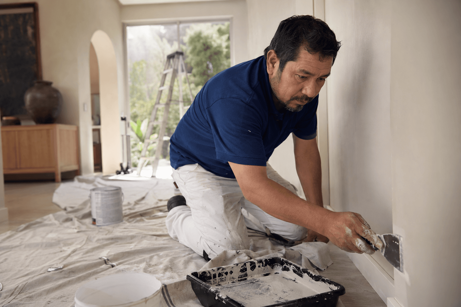 Un pintor prepara una pared dentro de una vivienda